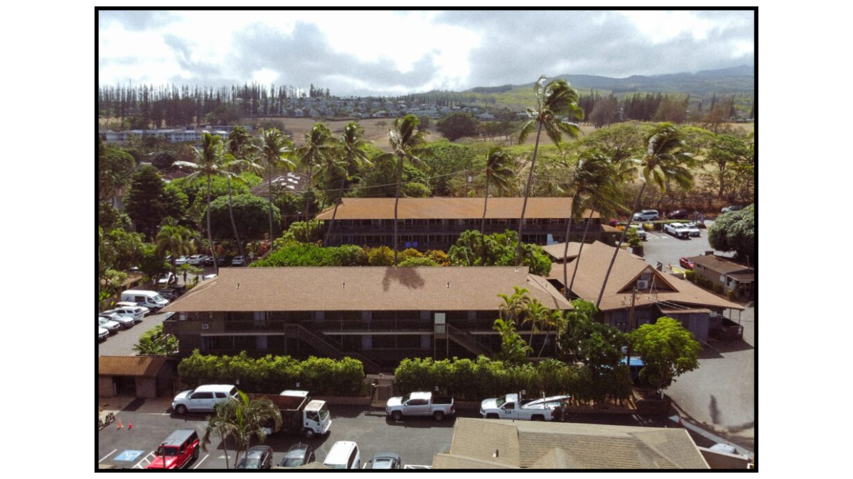 Napili Village Hotel, Aerial view of buildings surrounded by palm trees and greenery, with cars parked nearby.