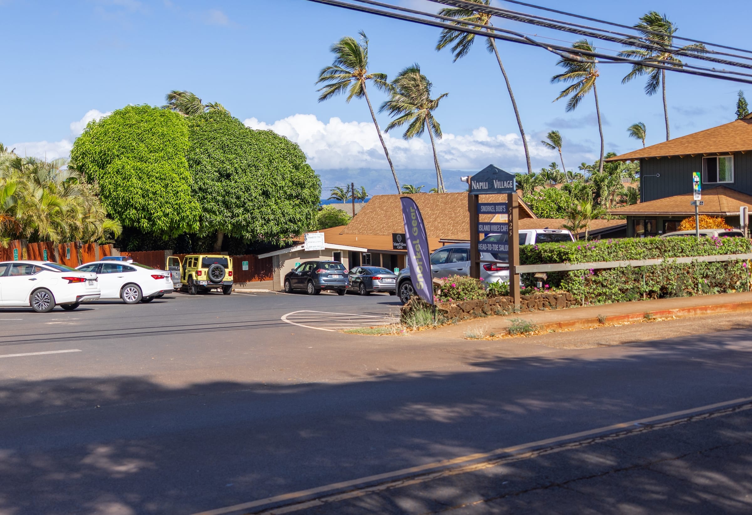 Napili Village Hotel, Napili Village in Maui with palm trees and Island Vibes Cafe sign.