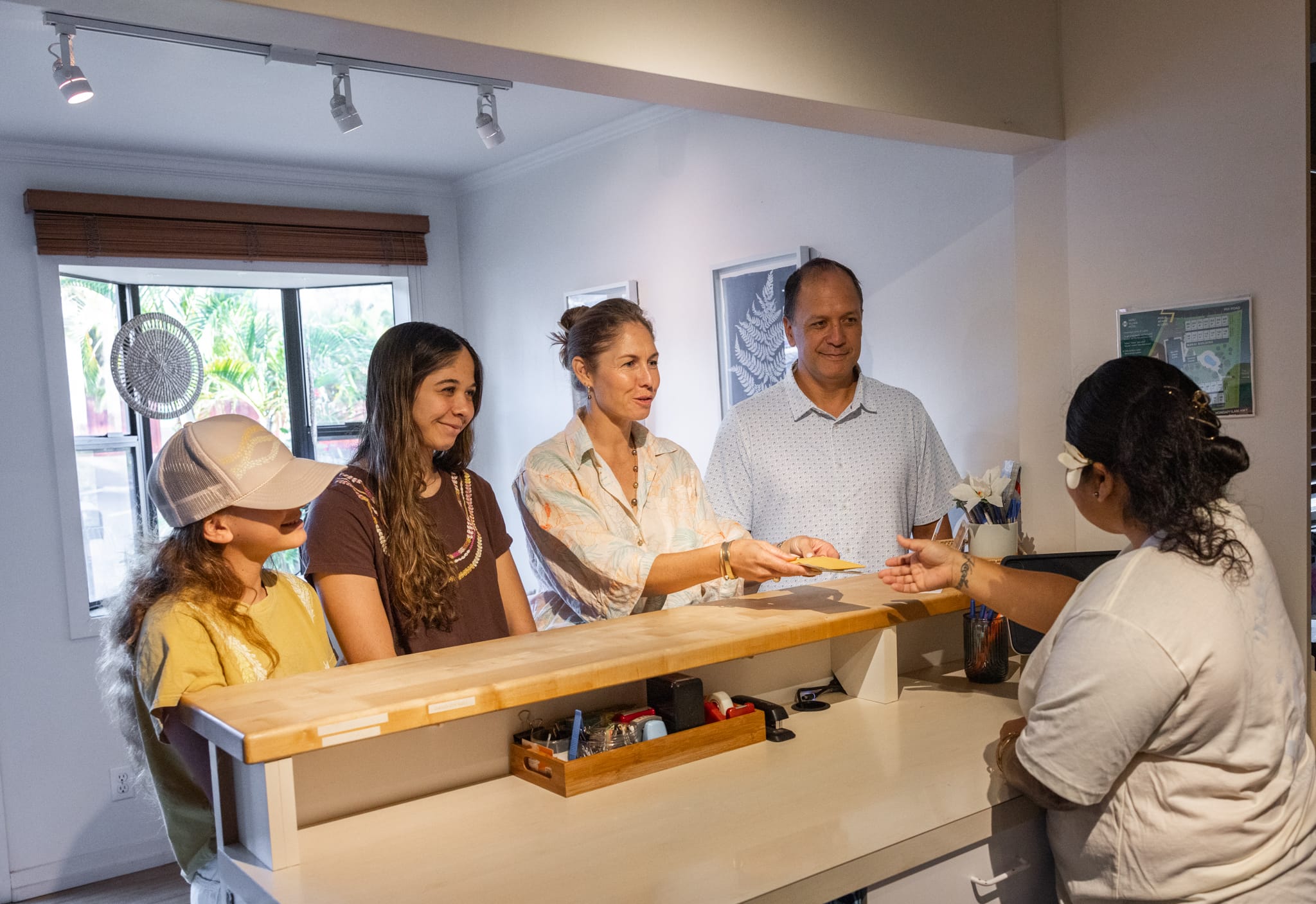 Napili Village Hotel, Family checking in at a hotel reception desk, receiving keys.